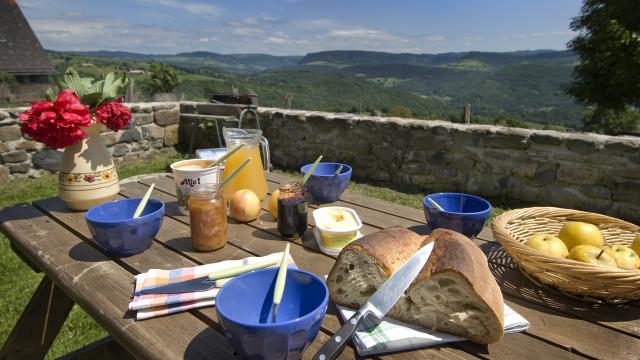 Breakfast on the terrace of an Aubrac gîte with local produce Bread, honey, jam, fruit ... and a beautiful panoramic view.