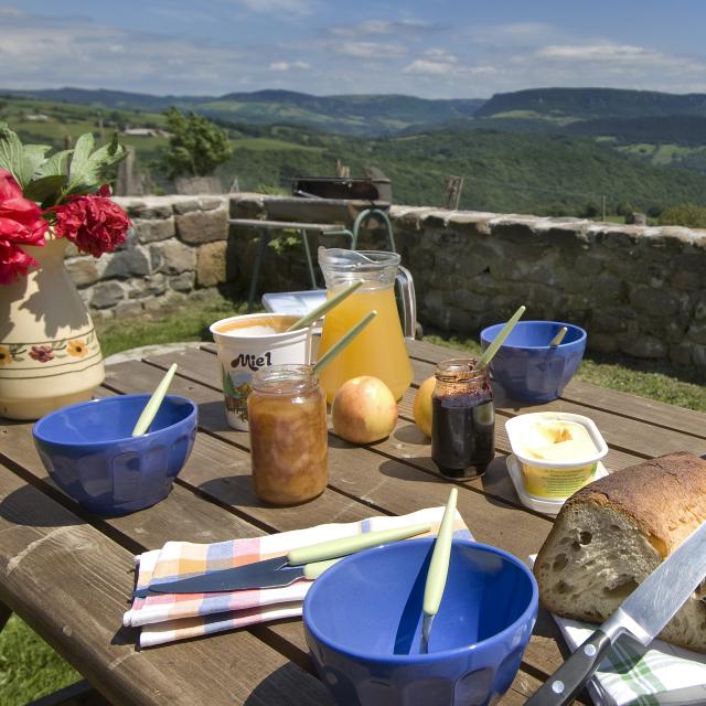Breakfast on the terrace of an Aubrac gîte with local produce Bread, honey, jam, fruit ... and a beautiful panoramic view.