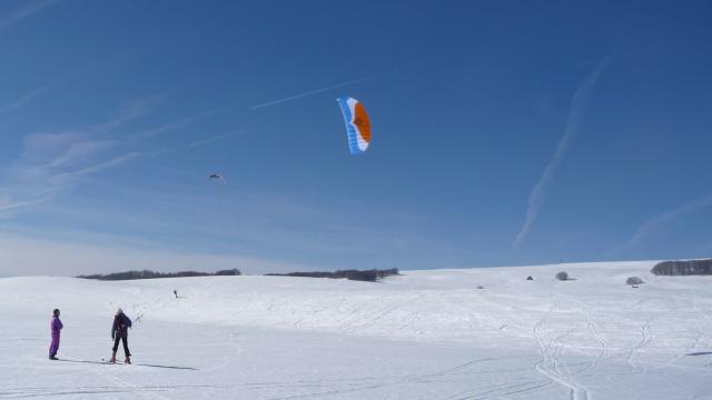 People snowkiting on the snow at Col de Bonnecombe in Aubrac.