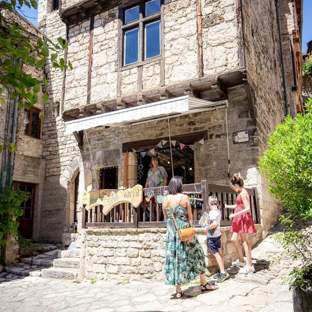 A family talks to a shopkeeper in Sainte-Enimie